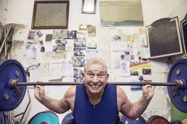 Sênior masculino powerlifter levantando barbell nos ombros no ginásio — Fotografia de Stock