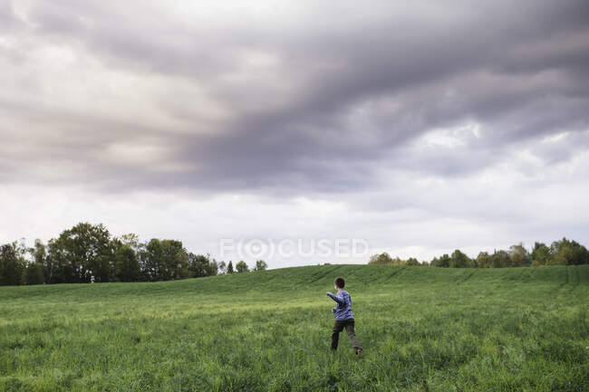 Garçon marchant sur le champ vert herbeux — Photo de stock