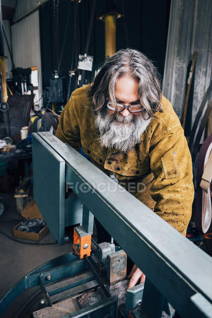 Blacksmith preparing machinery in metal workshop — Stock Photo