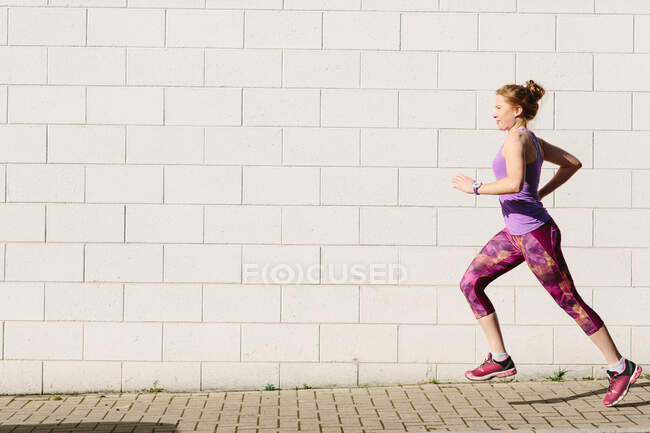 Jeune coureuse courant le long du trottoir — Photo de stock