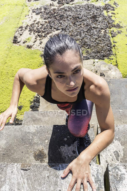 Young female free runner climbing up on sea wall — Stock Photo