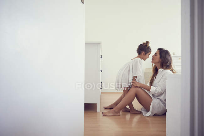 Young girl standing beside mother in bedroom, face to face — Stock Photo