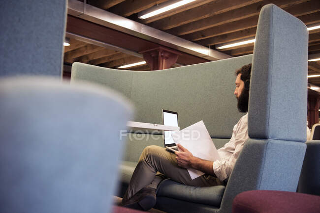 Side view of man in booth using laptop — Stock Photo