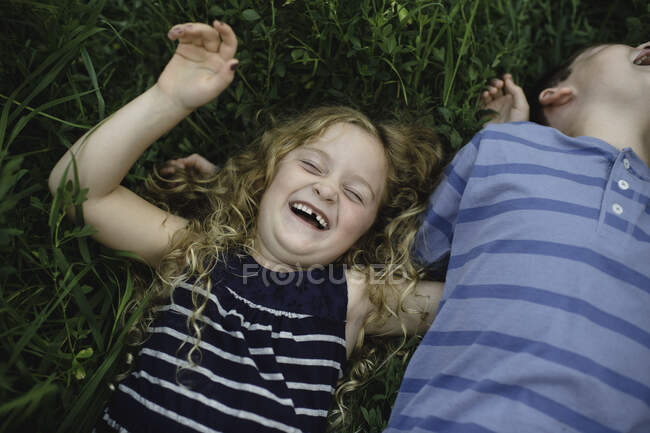 Brother and sister enjoying outdoors on green grassy field — Stock Photo