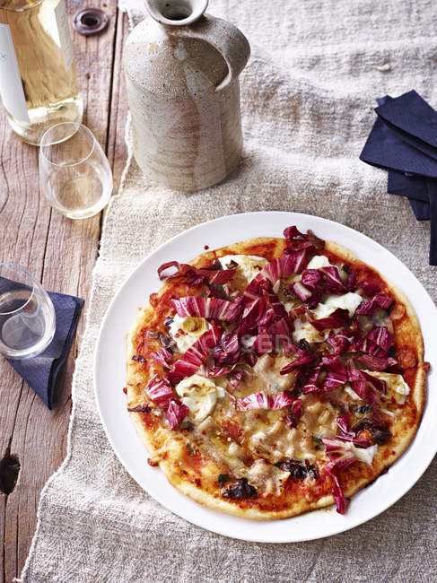 Свиной живот, цикорий и бальзамическая пицца на белой тарелке, возвышенный вид — стоковое фото