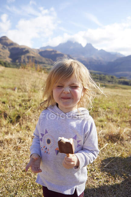 Niña comiendo lolly hielo, en un entorno rural - foto de stock
