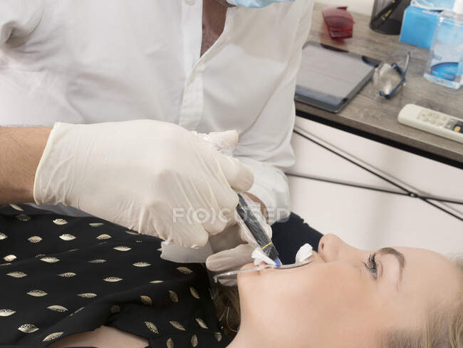 Junge Frau im Zahnarztstuhl, Zahnärztin bereitet Frau auf zahnärztlichen Eingriff vor — Stockfoto