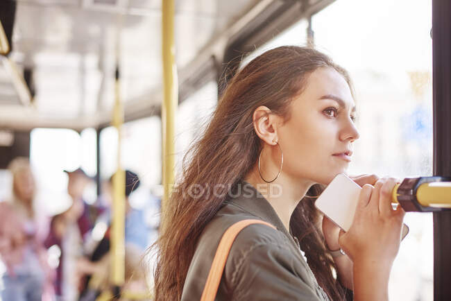 Jeune femme sur le tramway de la ville regardant par la fenêtre — Photo de stock