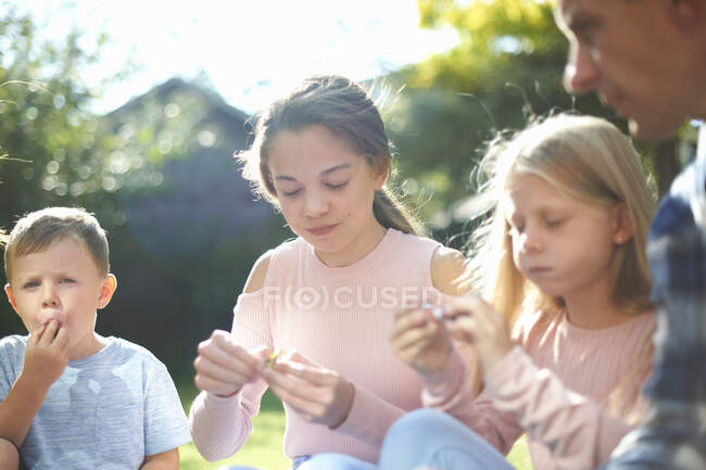 Father and children, sitting in garden, eating sweets — Stock Photo
