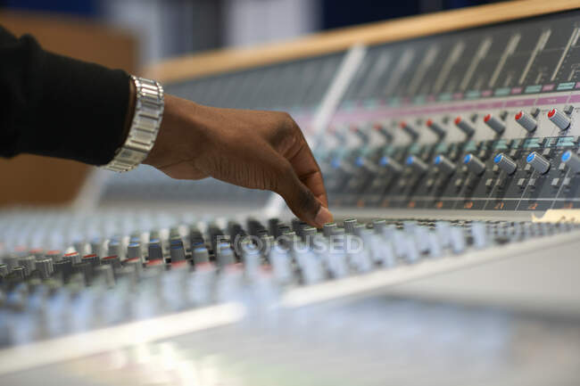 Hand of male college student at sound mixer in recording studio — Stock Photo