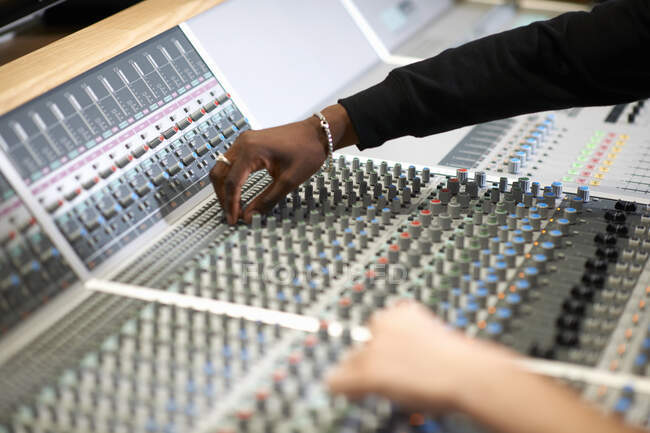 Hands of male college students at sound mixer in recording studio — Stock Photo