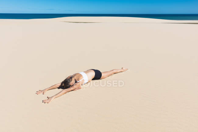 Frau am Strand liegt vorne in Yogaposition — Stockfoto