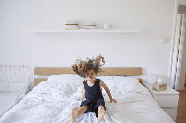 Junges Mädchen springt auf Bett — Stockfoto