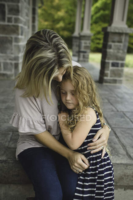 Mãe consoladora filha na varanda da frente — Fotografia de Stock