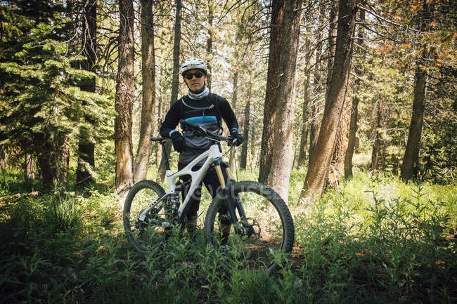 Hombre en el bosque con bicicleta de montaña, mirando a la cámara, Mammoth Lake, California, Estados Unidos, América del Norte - foto de stock