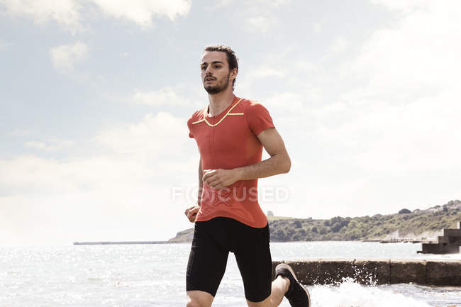 Junger Mann läuft am Strand entlang — Stockfoto