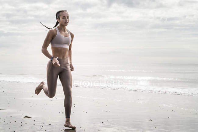 Молода жінка біжить вздовж берега — стокове фото