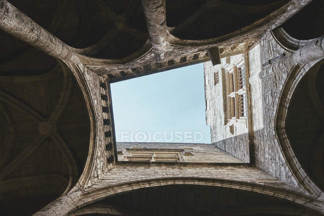 Vista de bajo ángulo del claustro de la iglesia y el cielo azul, Pezenas, región de Occitanie, Francia - foto de stock