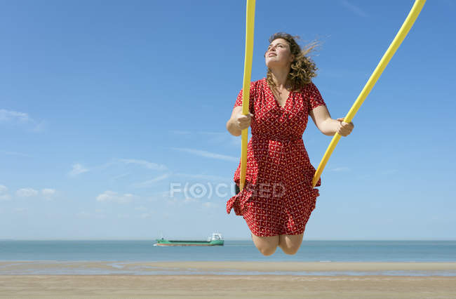 Mujer vestida balanceándose en la playa, Zoutelande, Zelanda, Países Bajos, Europa - foto de stock