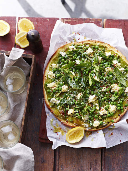 Spring peas, mint and salted ricotta pizza on serving board, elevated view — Stock Photo