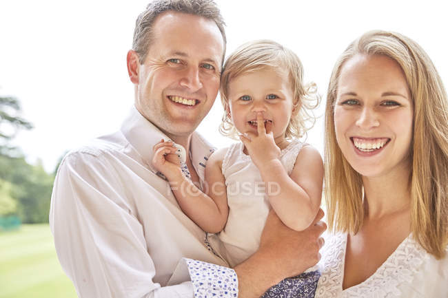 Retrato de casal com bebê filha sorrindo para a câmera — Fotografia de Stock