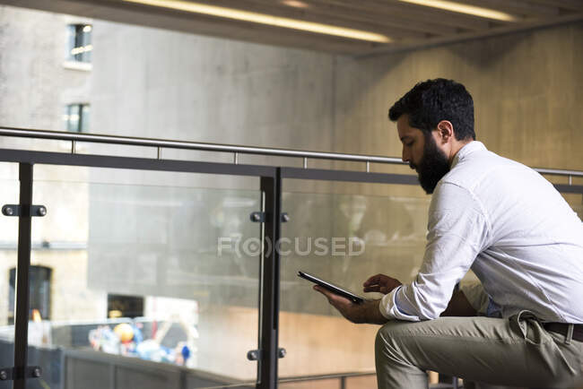 Чоловік на мезаніні в офісному будинку з використанням цифрового планшета — стокове фото