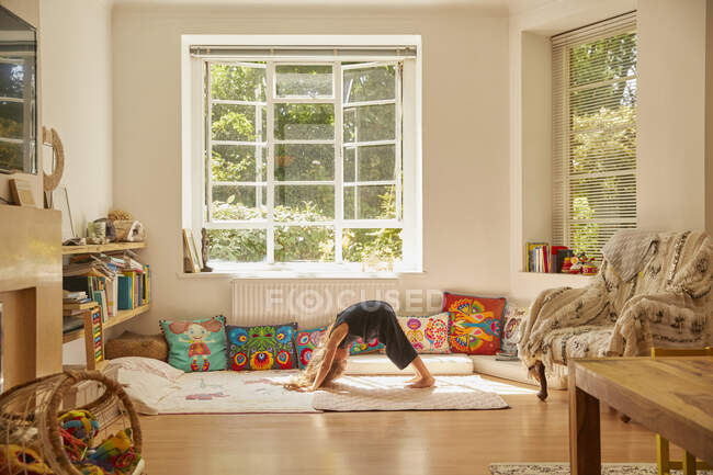 Jovem em casa, curvada na posição de ioga — Fotografia de Stock