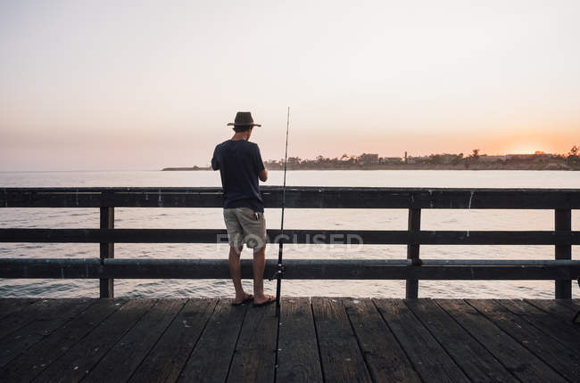 Rear view of man on pier fishing, Goleta, Калифорния, США, Северная Америка — стоковое фото
