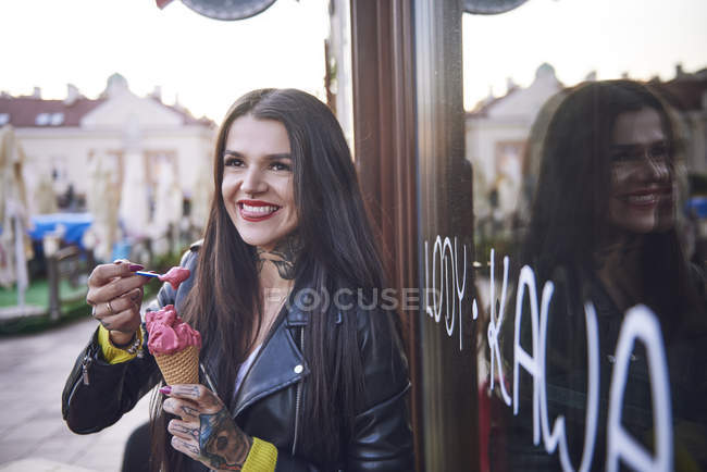 Portrait of young woman eating ice cream, tattoos on hand — Stock Photo