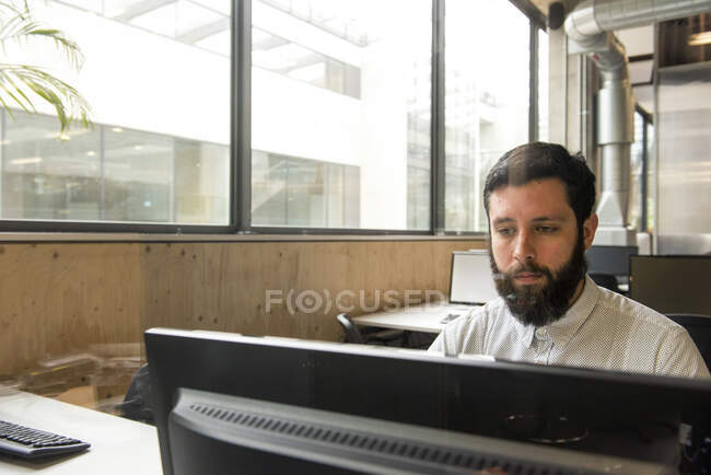 Hombre en la oficina usando computadora de escritorio - foto de stock