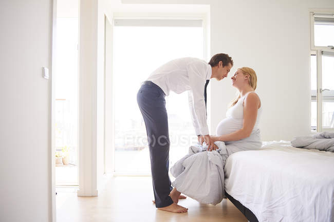 Romántica pareja embarazada cara a cara en el dormitorio - foto de stock