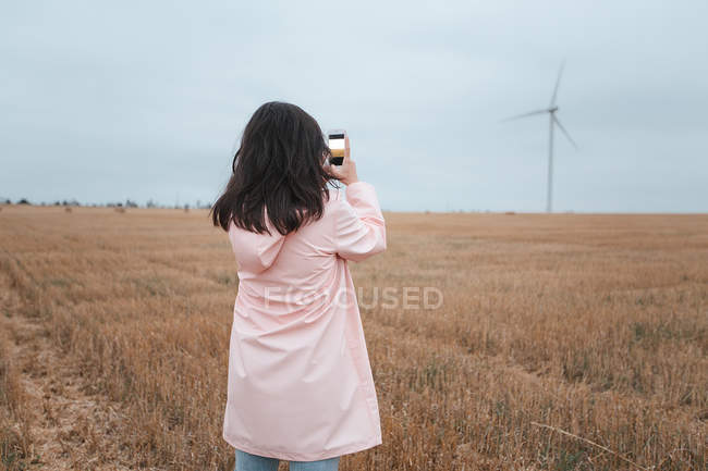 Mujer en impermeable tomando fotos en el campo, Odessa, Ucrania - foto de stock