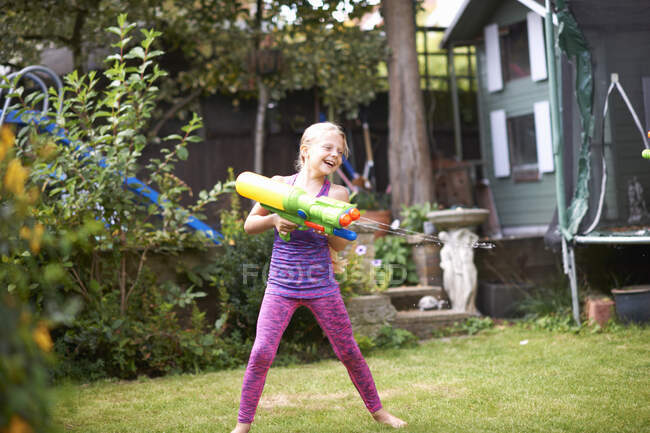 Mädchen spritzt Wasserpistole in Garten — Stockfoto
