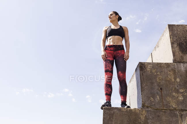Young female runner looking out from top of sea wall — Stock Photo