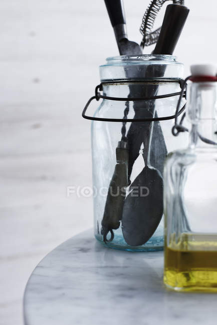 Пляшка оливкової олії та кухонного начиння крупним планом — стокове фото