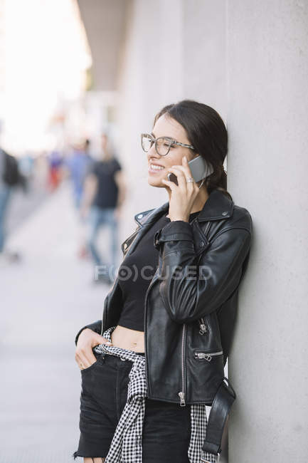 Mujer apoyada contra la pared usando smartphone - foto de stock