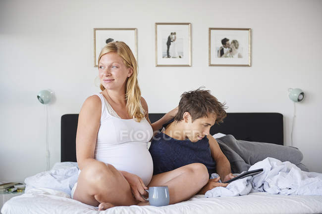 Mann und schwangere Freundin entspannen sich auf Bett — Stockfoto