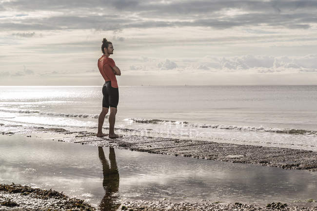 Hombre en la costa mirando hacia otro lado en vista del mar - foto de stock