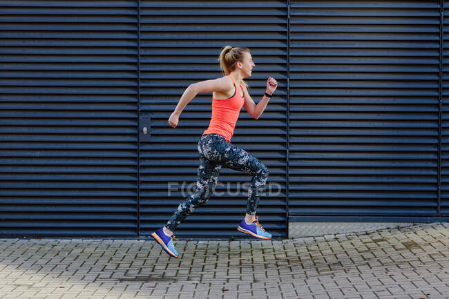 Молодая бегунья бежит по тротуару — стоковое фото
