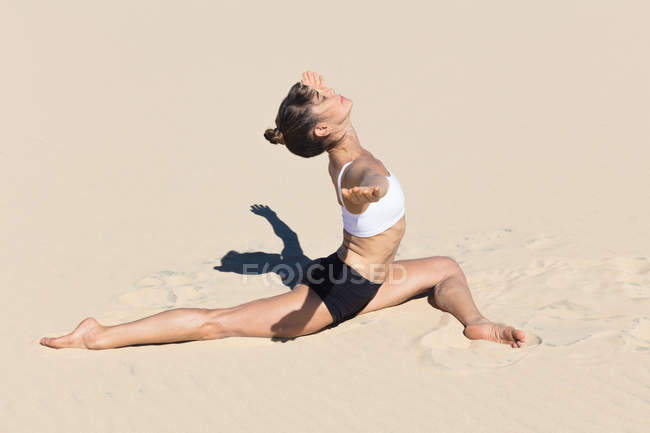Vue latérale de la femme sur la plage faisant du yoga — Photo de stock