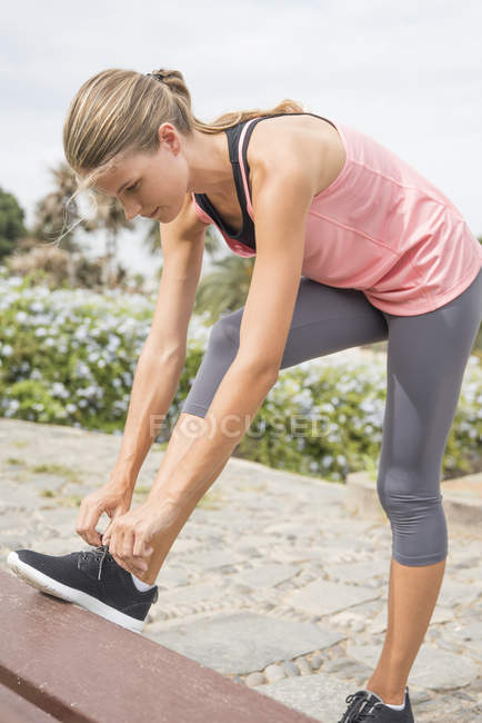 Femme en vêtements de sport attachant lacet — Photo de stock
