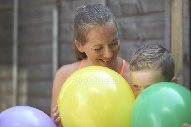 Madre e hijo en el jardín, sosteniendo globos - foto de stock