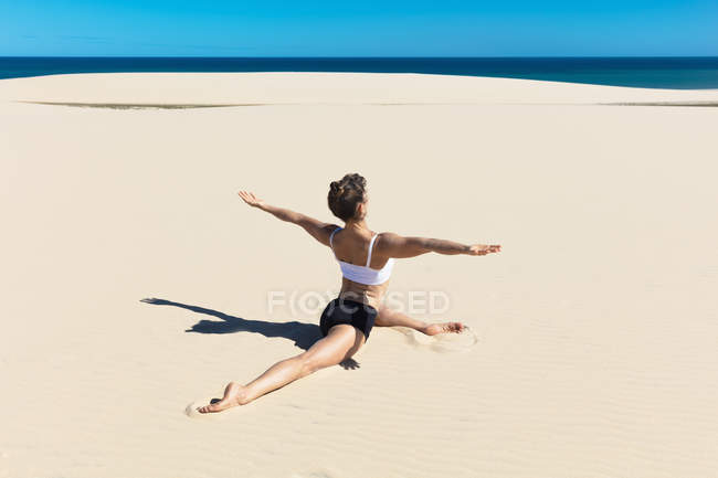 Rear view of woman on beach in yoga position — Stock Photo