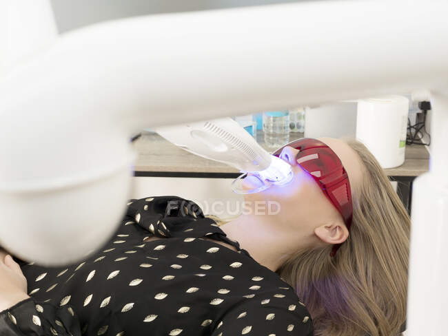 Jovem mulher em cadeira de dentista, tendo dentes clareados — Fotografia de Stock