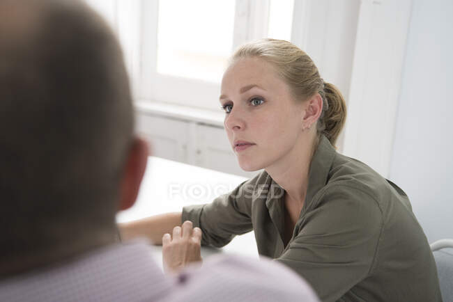 Over shoulder view of young businesswoman having meeting at office desk — Stock Photo