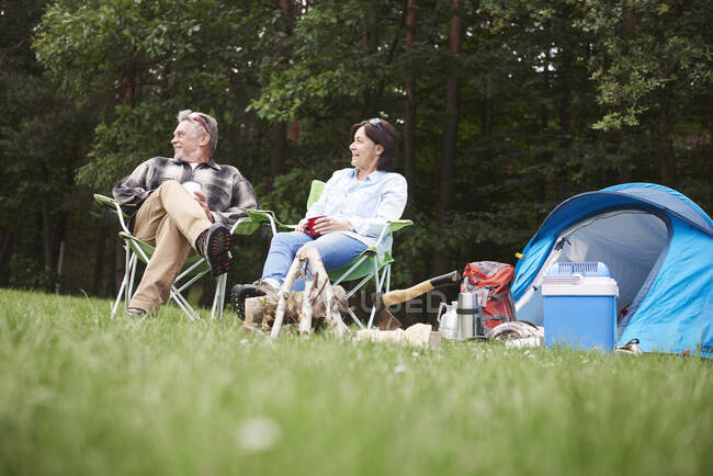Зрелая пара, сидящая в кемпингах рядом с палаткой, вид с низкого угла — стоковое фото
