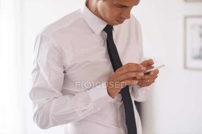 Бізнесмен дивиться на смартфон у вітальні — стокове фото