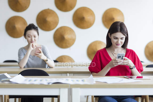 Estudantes usando telefone celular enquanto esperam na aula — Fotografia de Stock