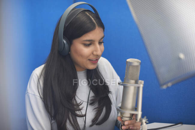 Young female college student at microphone in TV recording studio — Stock Photo