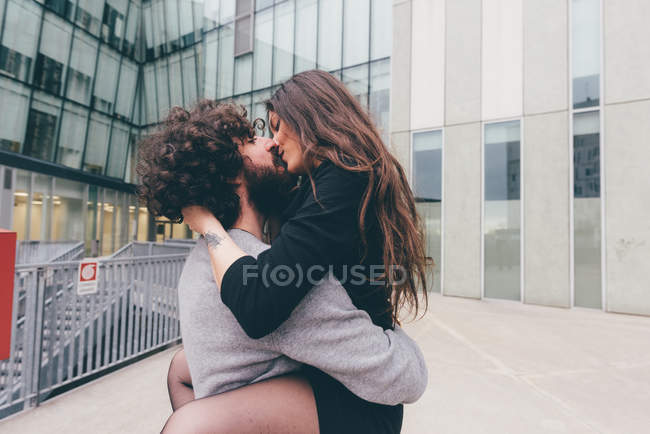 Молода пара на відкритому повітрі, поцілунки, жіночі ноги обгорнуті навколо чоловіка — стокове фото